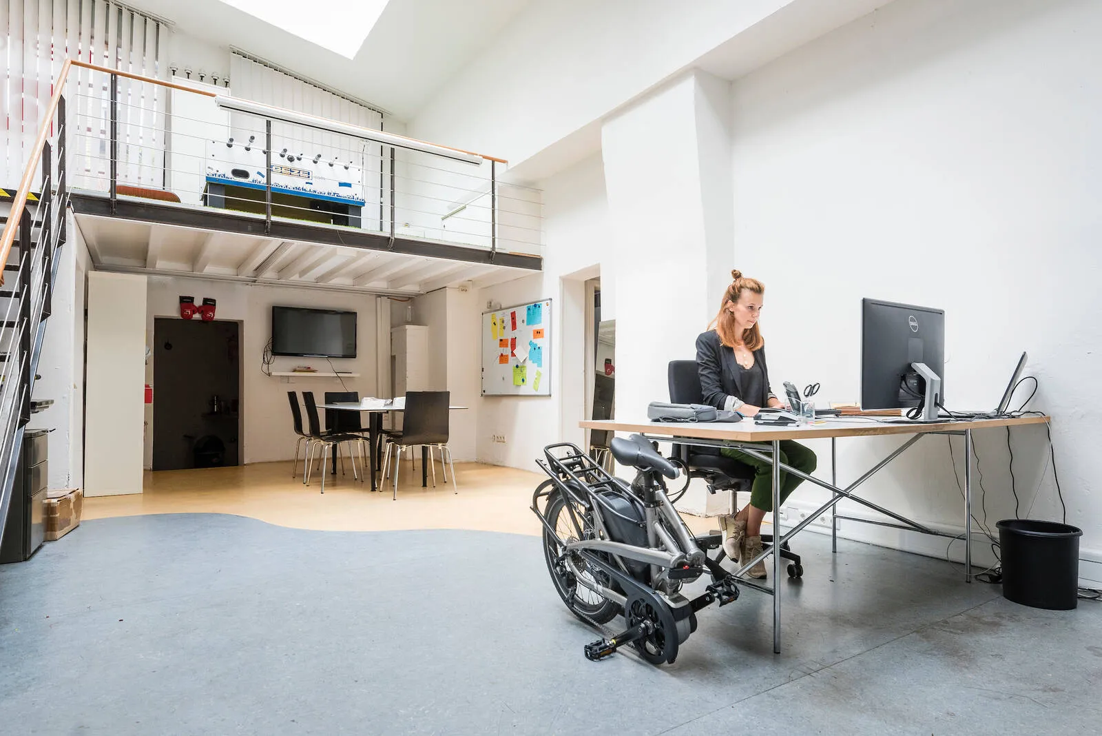 A person with their Tern Vektron folded up next to their desk