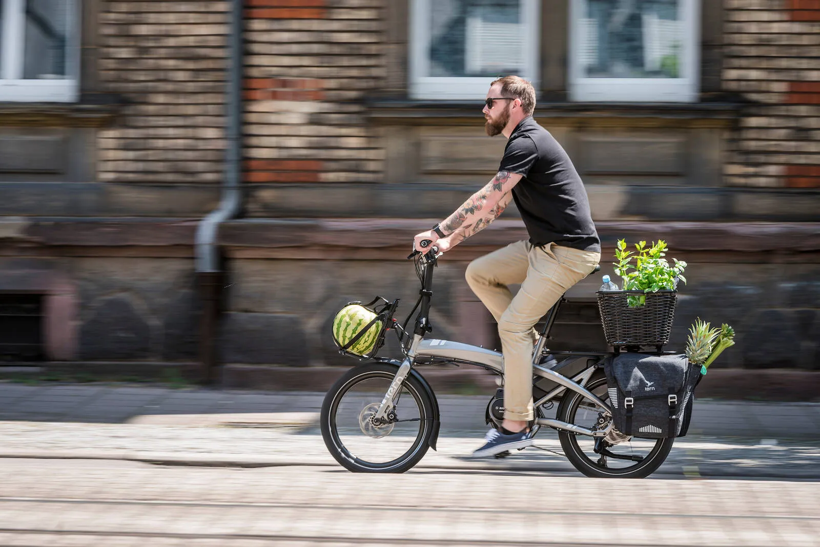 A person riding a Tern Vektron loaded with fruit and veg along a street