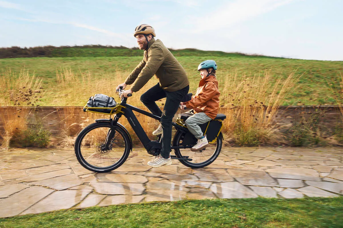 Father and child cycling together on Multicharger2 along stone pathway.
