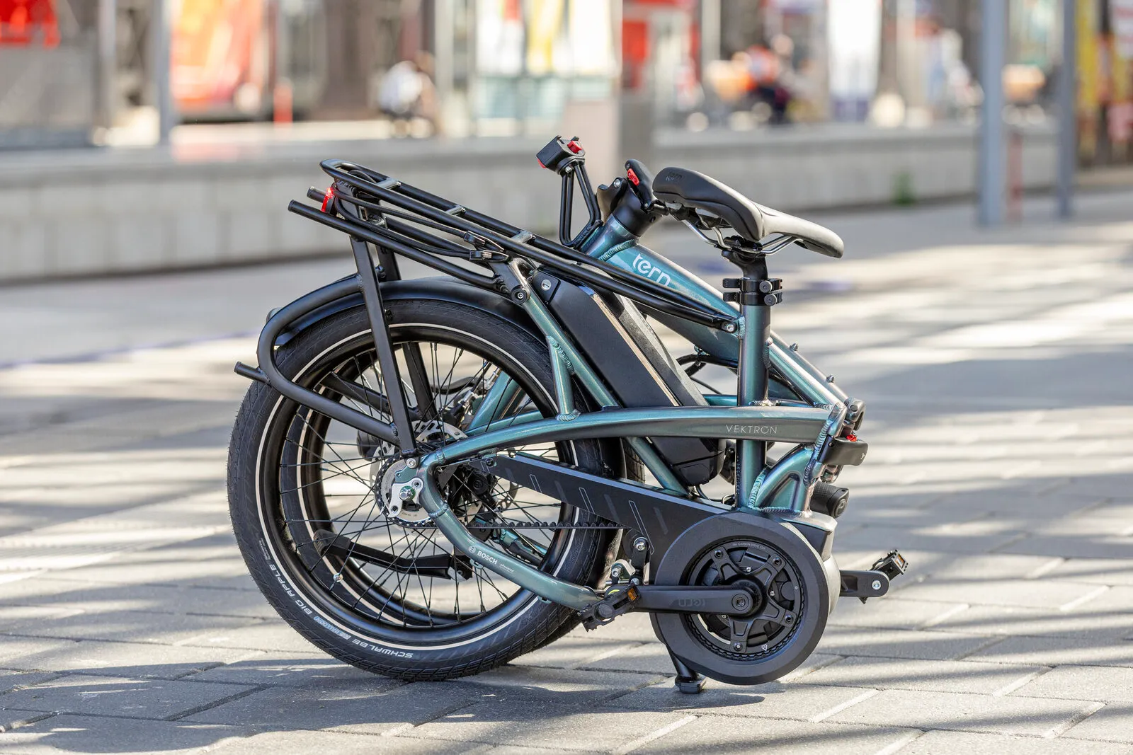 The Tern Vektron in urban verdant folded on a city street.