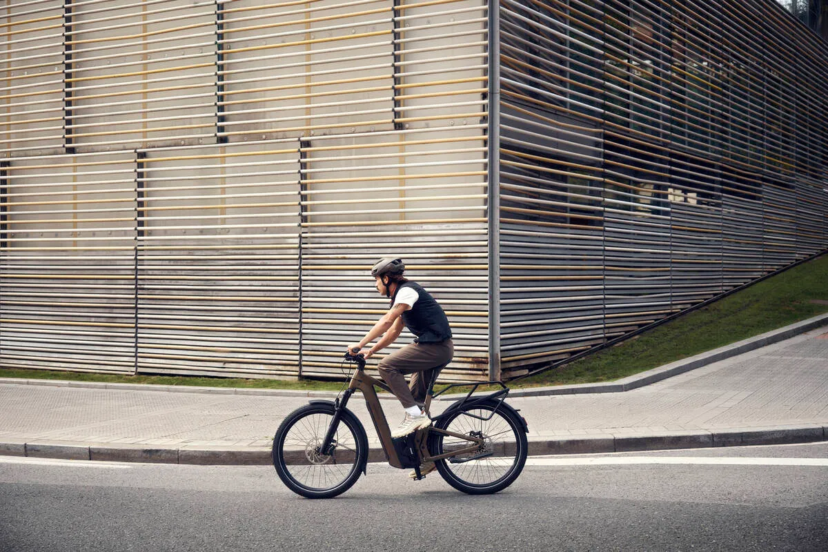 A man riding Riese & Müller’s Delite5 along a street in front of a wooden structure.