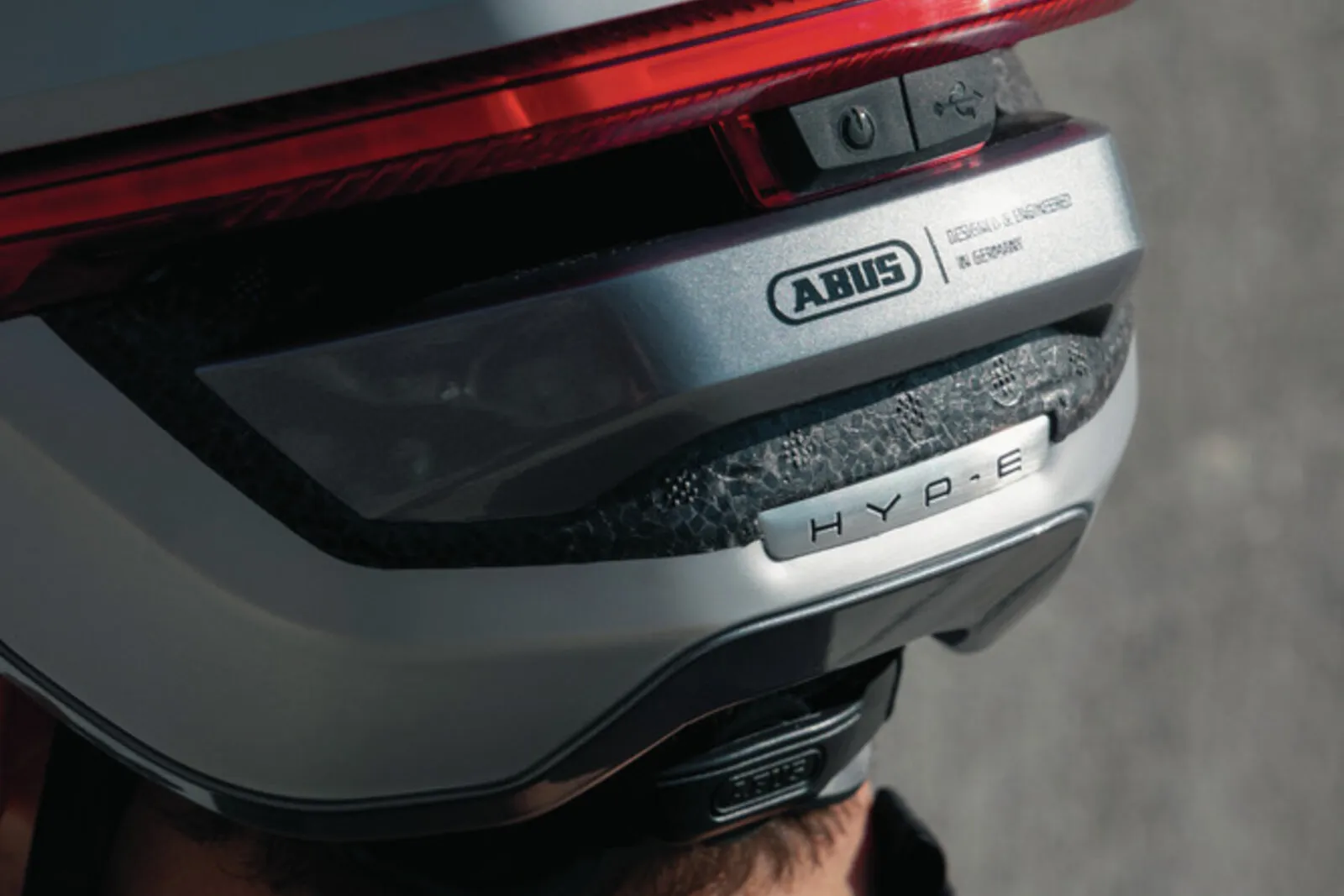 Rider wearing the ABUS HYP-E BL.ACE helmet in gleam silver while cycling in an urban setting