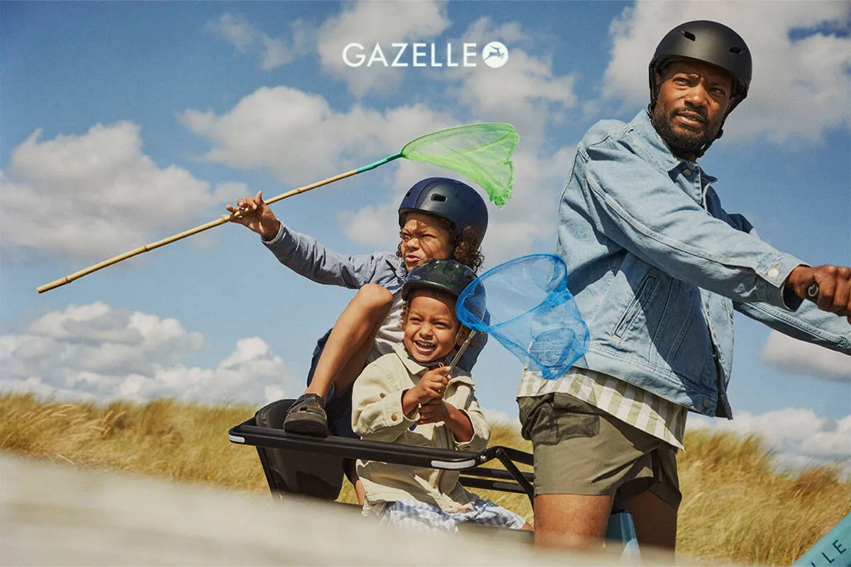 Children on Gazelle Cabby’s rear carrier holding butterfly nets, with adult cycling on sunny day