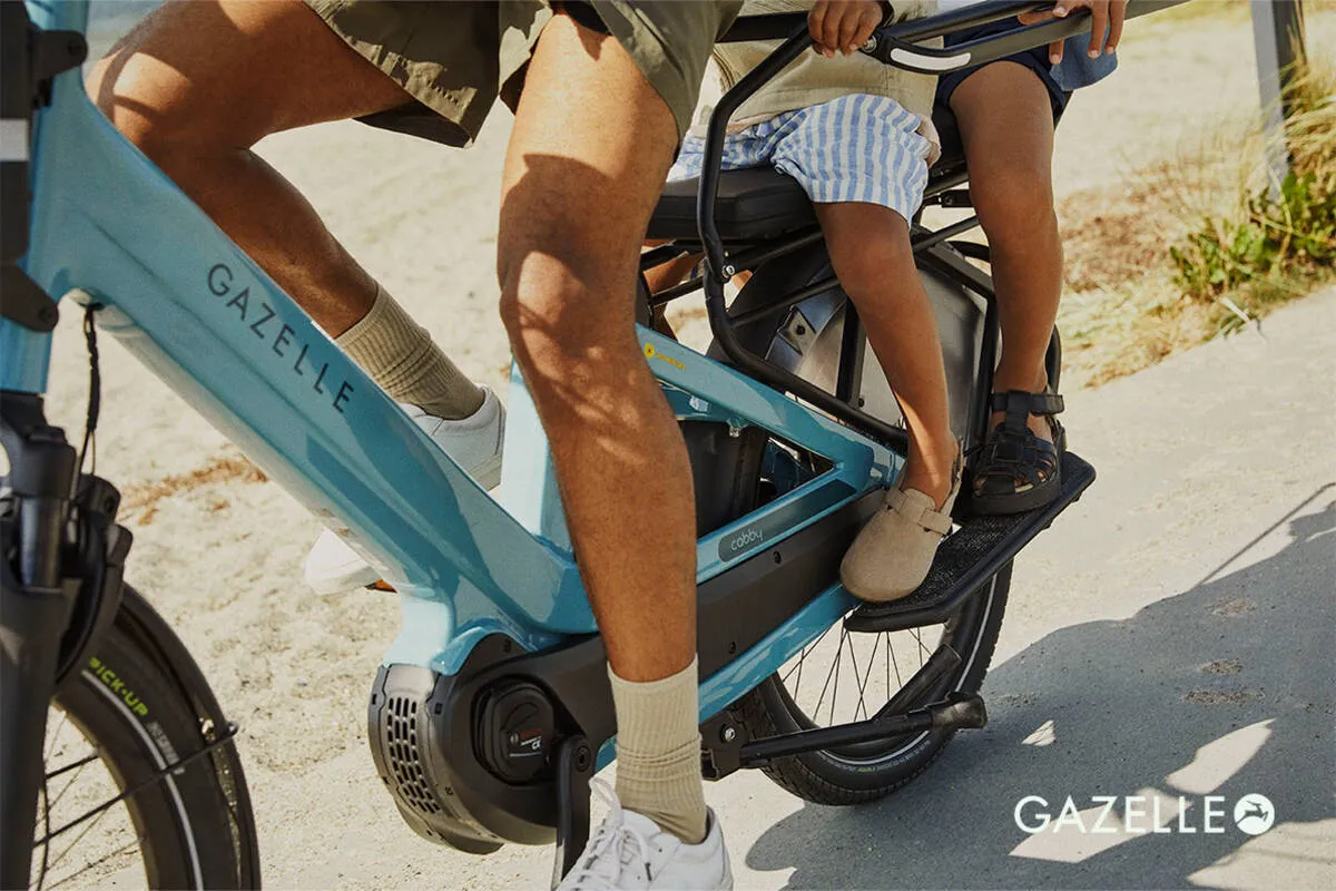 Close-up of Gazelle Cabby e-bike frame showing denim blue gloss finish, motor housing and passenger footrests