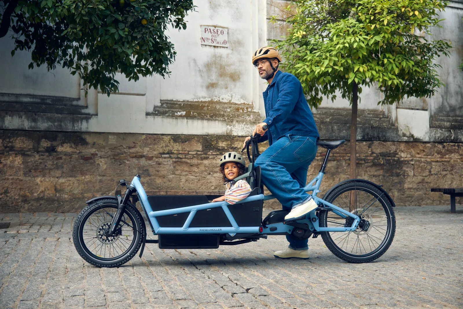 Rider on the Load5 75 vario in arctic with a smiling child wearing a helmet in the cargo box, side profile view.