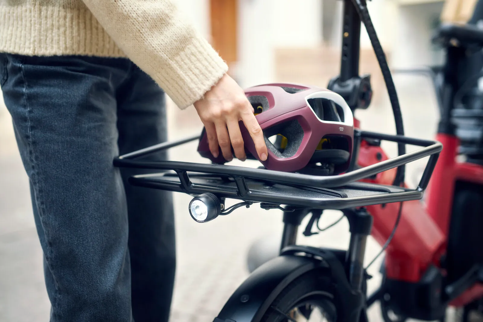 Close-up of the Multitinker2 front carrier with a helmet placed on the rack, showing the integrated headlight.