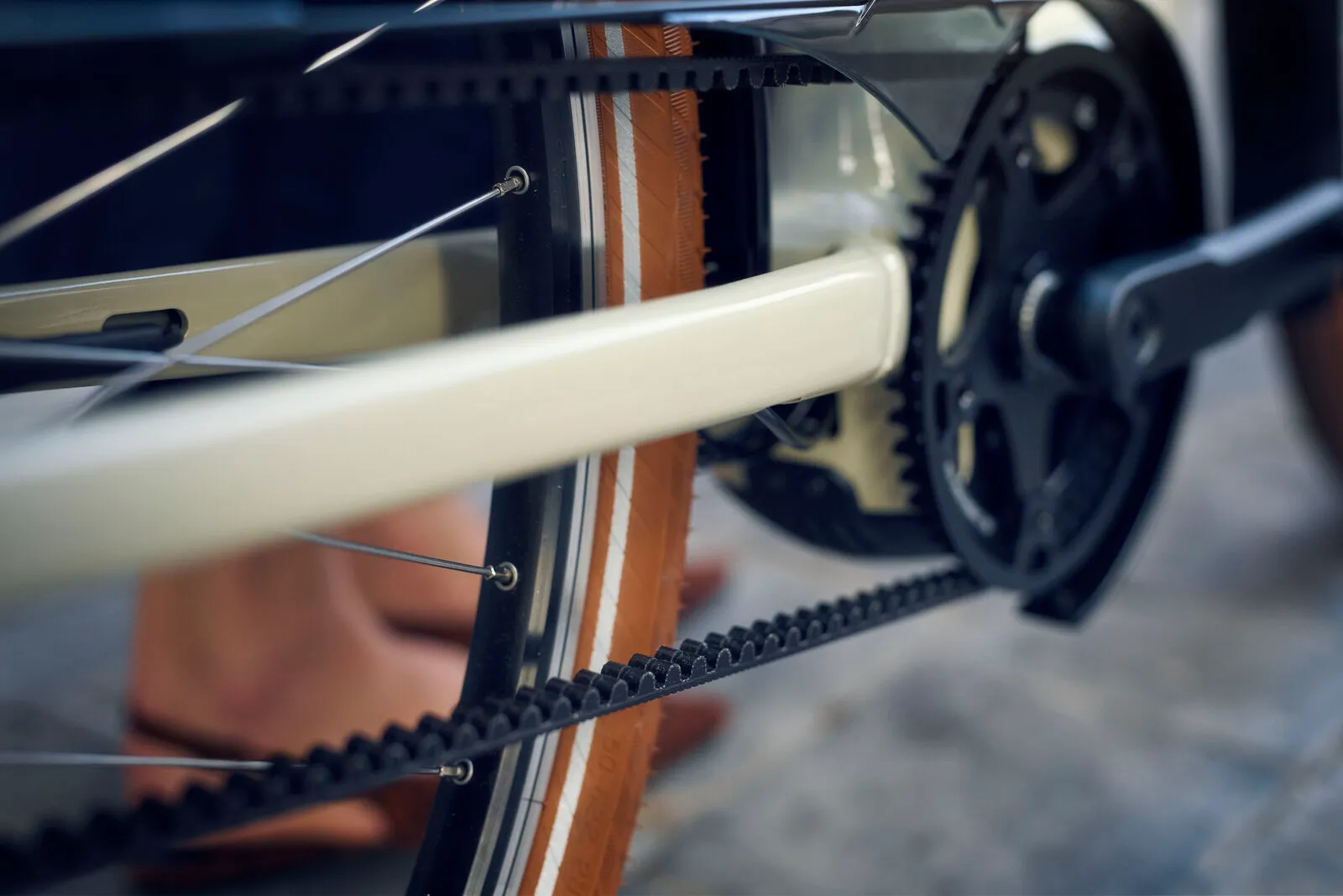 Close-up of the Swing5 Gates carbon belt drive and tan wall tyres on the almond frame.