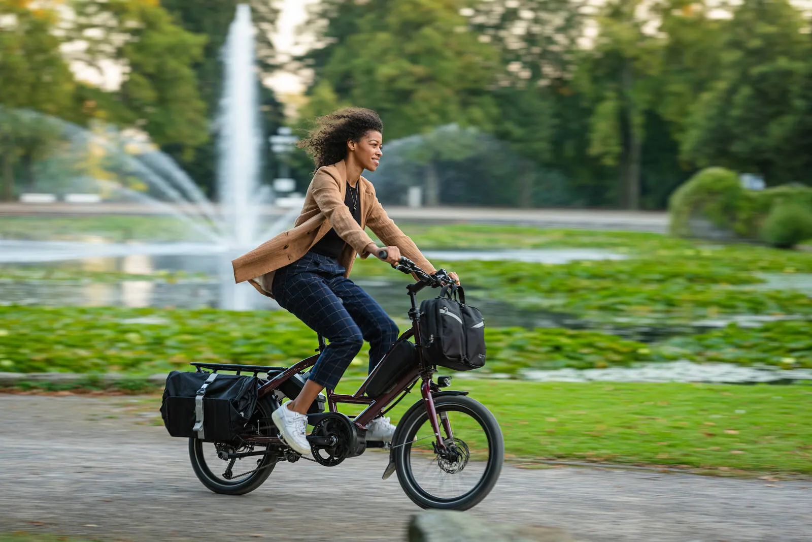 A lady riding a Tern Quick Haul on her commute through a park