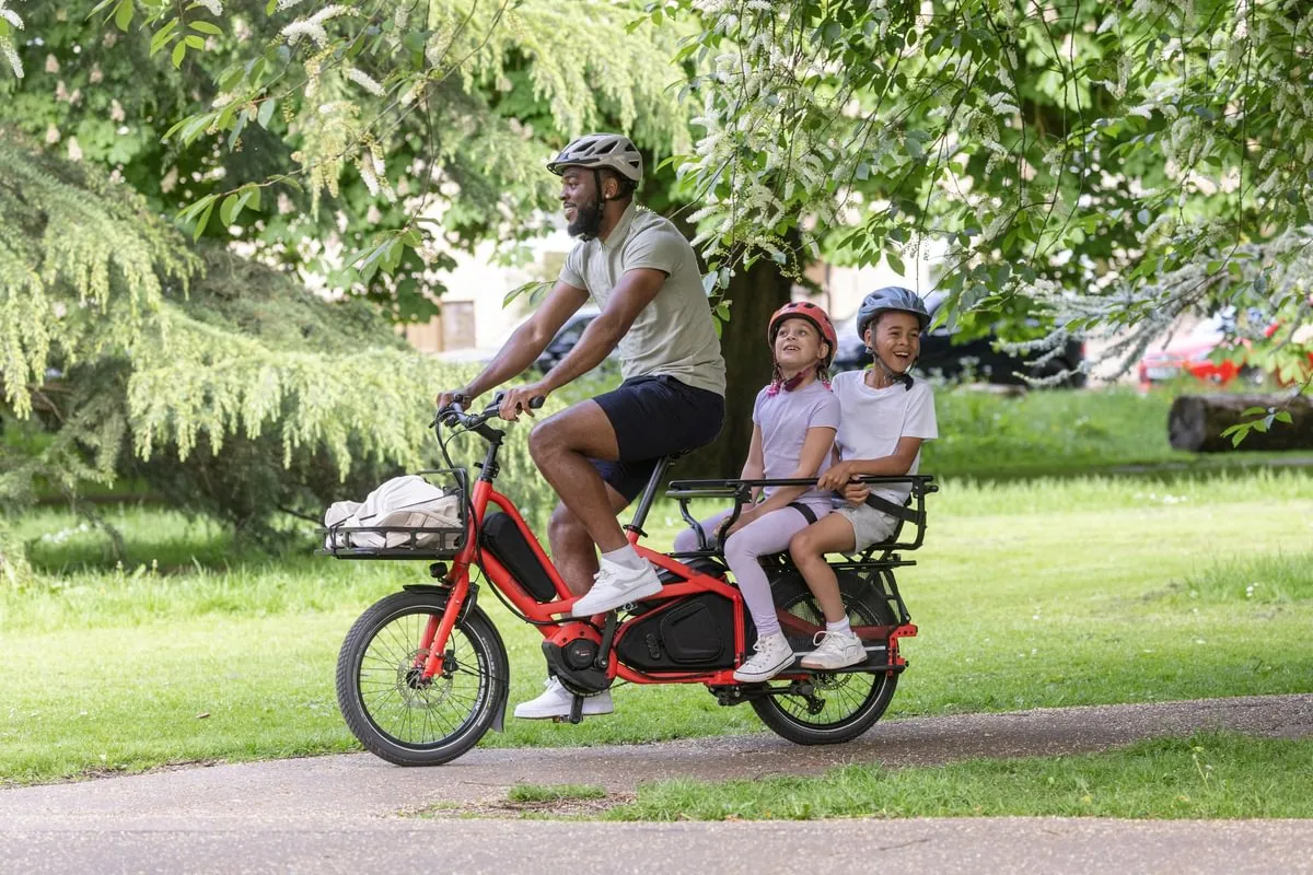 A lady riding a Tern Quick Haul on her commute through a park