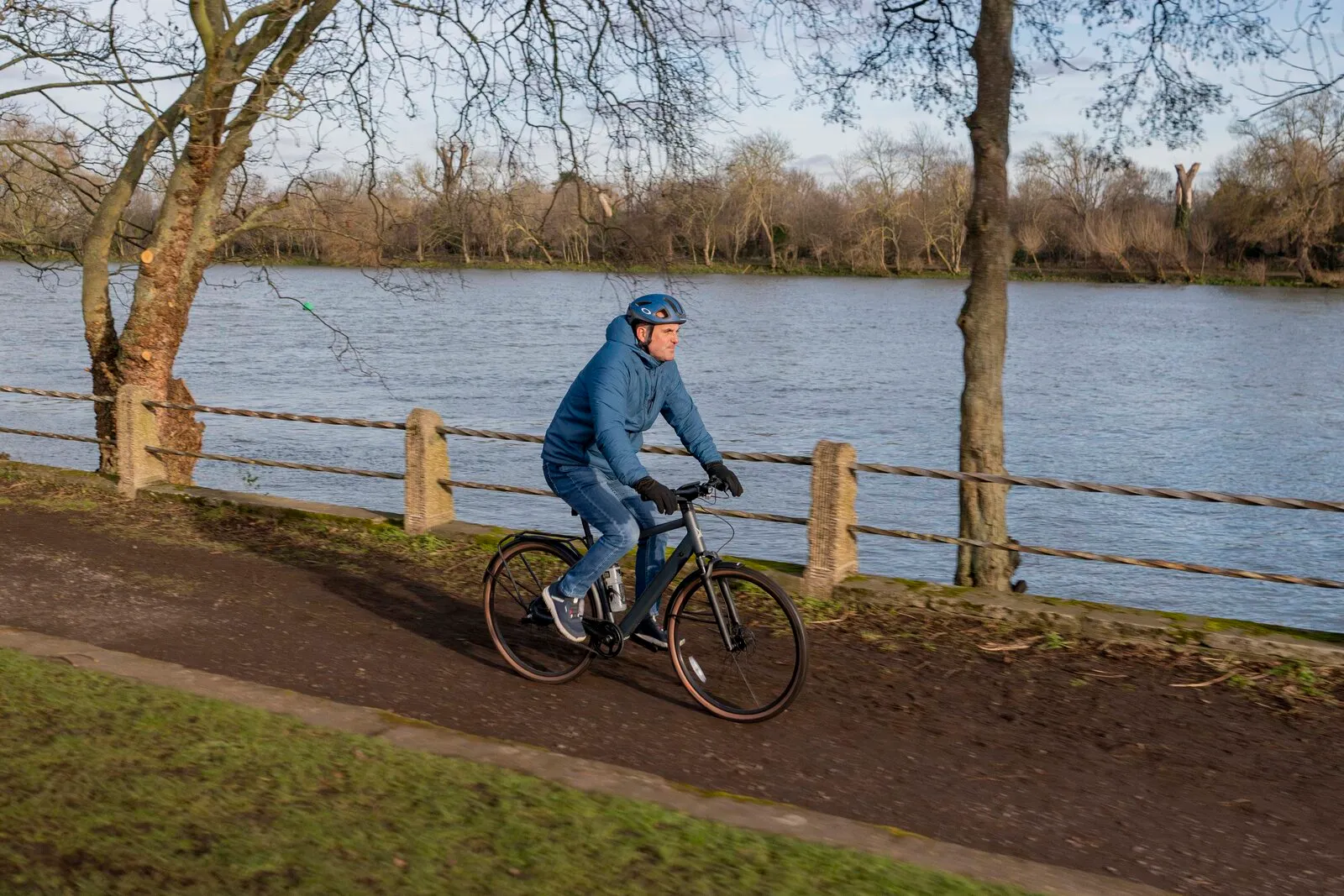 A man cycling the Estarli e28.X crossbar along a riverside path.