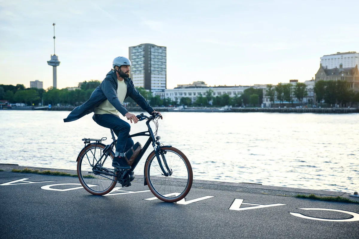 A man riding a Riese & Müller Cruiser2 along a	cycle path next to a river.