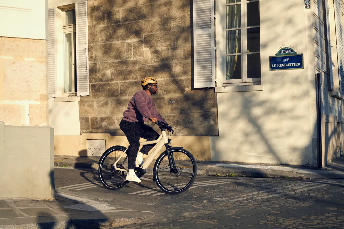 A man cycling on a Riese & Müller Culture e-bike around the corner of a cobbled street in Paris.
