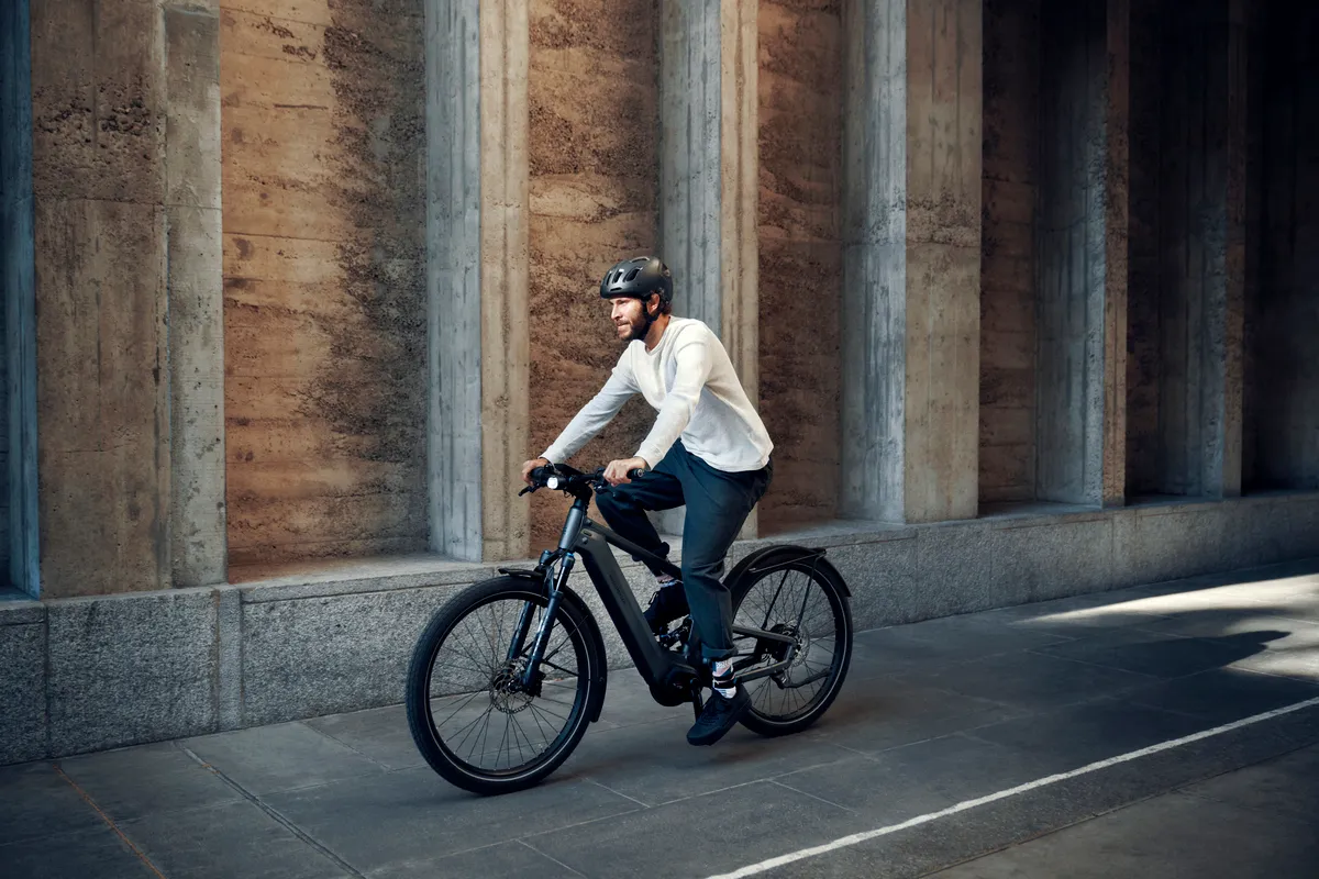 A man riding Riese & Müller’s Delite along a paved street in front of a textured marble wall.