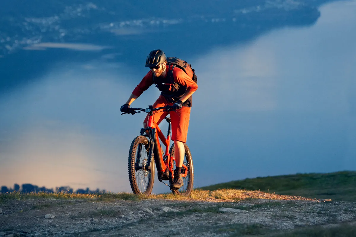 A man climbing a steep off-road trail on a Riese & Müller Delite mountain e-bike.