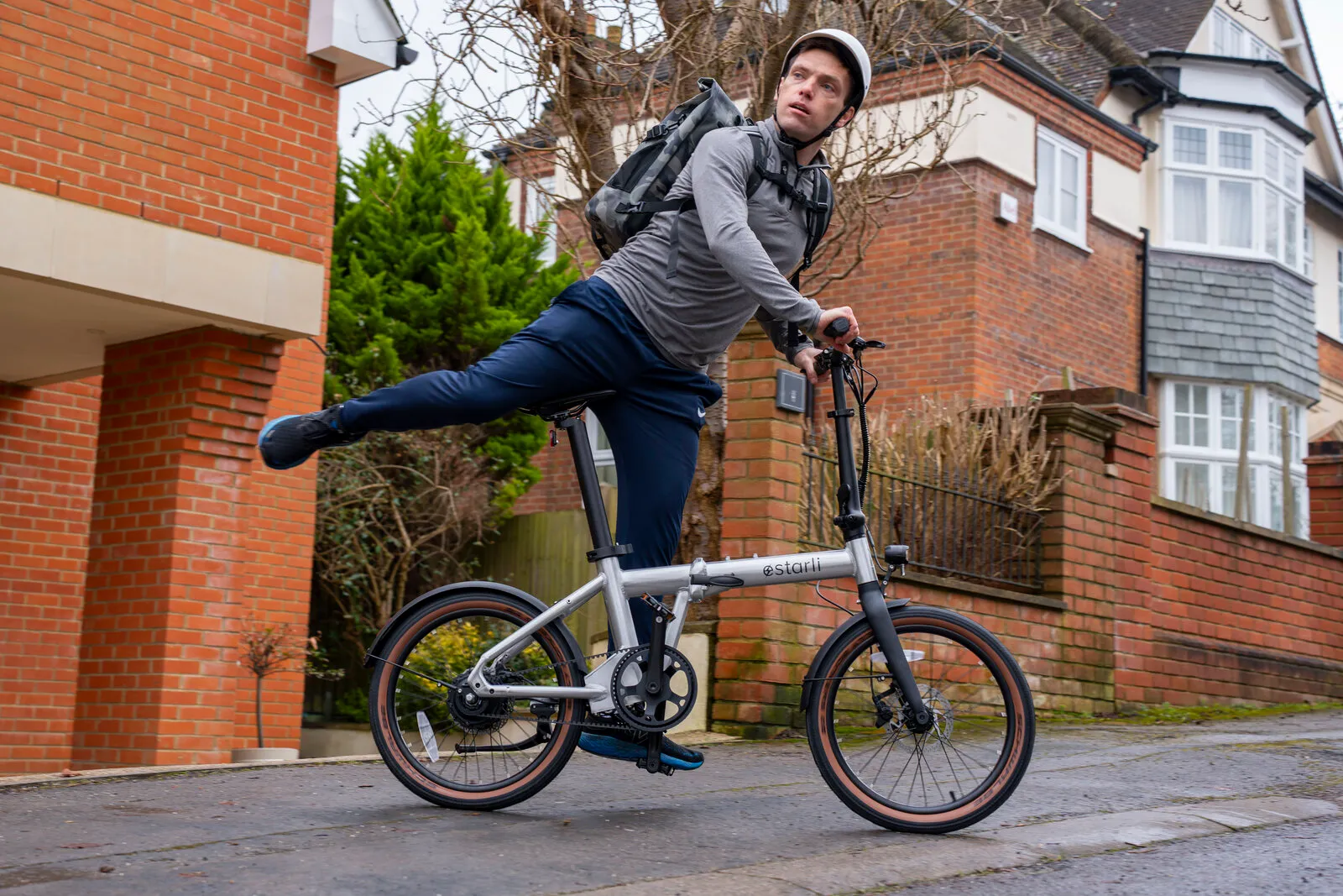 A man riding the Estarli e20.X in a suburban street with a backpack.