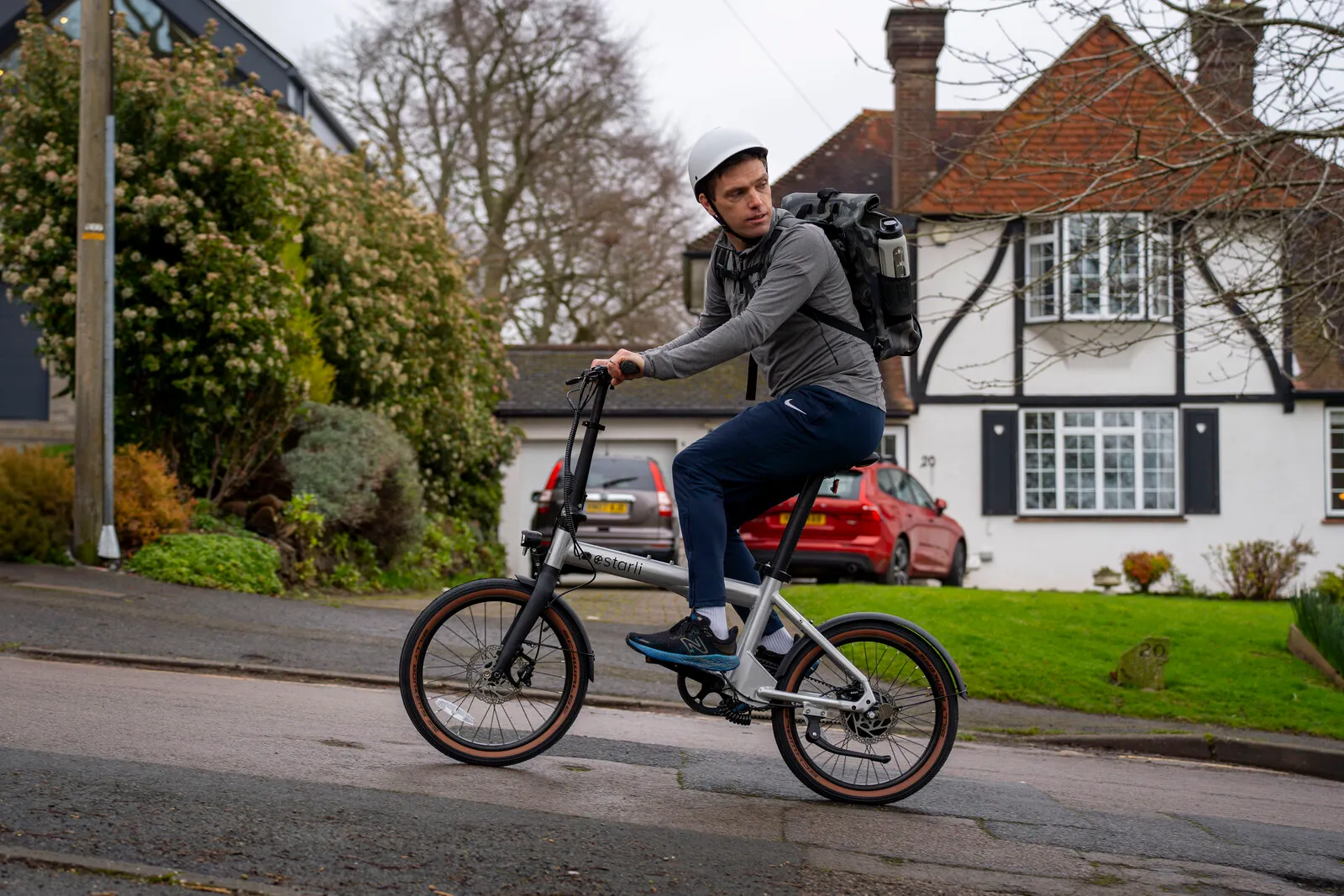 A man cycling the Estarli e20.X uphill in a residential area.