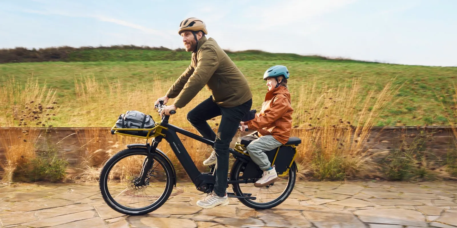 A father and son cycling along a towpath on a Riese & Müller Multicharger