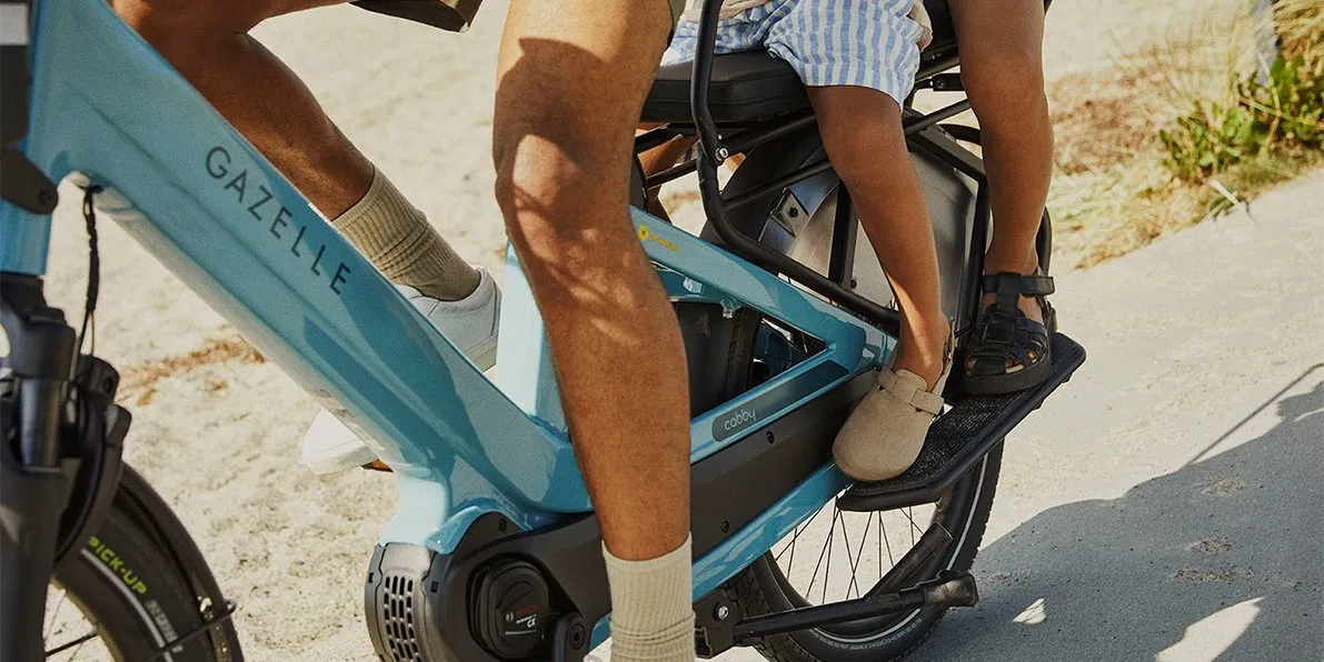 A close-up of Gazelle Cabby transporting a father and two children along a sandy path