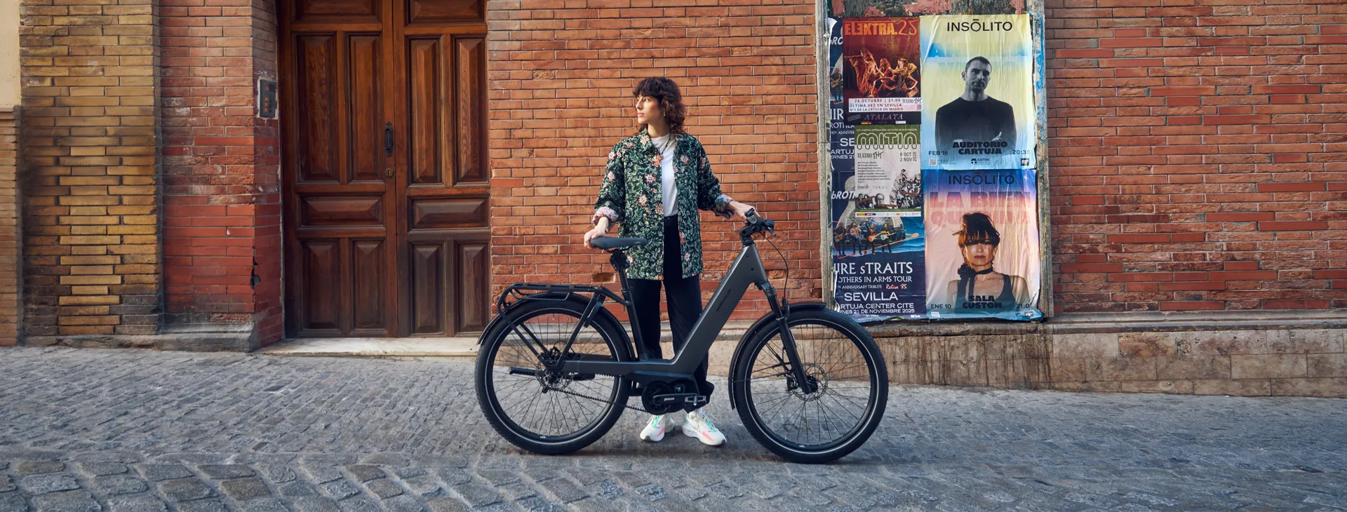 A woman standing with a Riese & Müller Nevo on a cobbled street