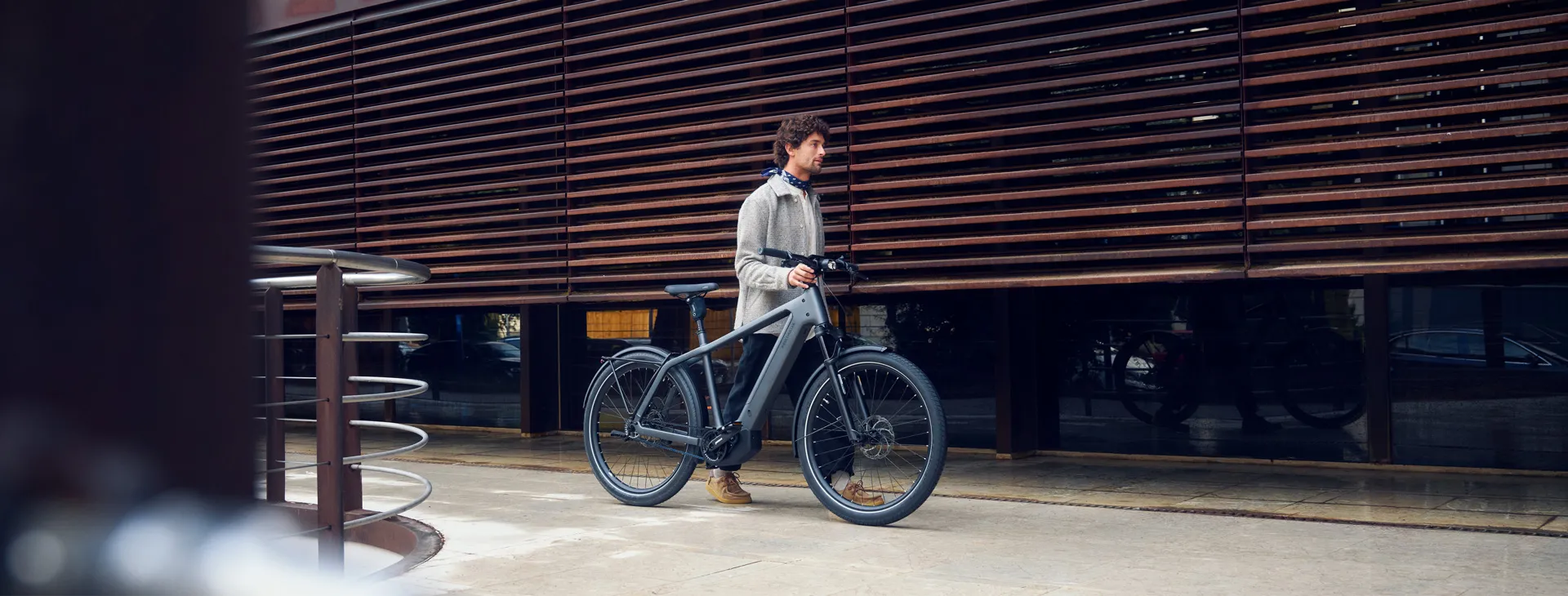 A man walking with a Riese & Müller Charger outside a modern building