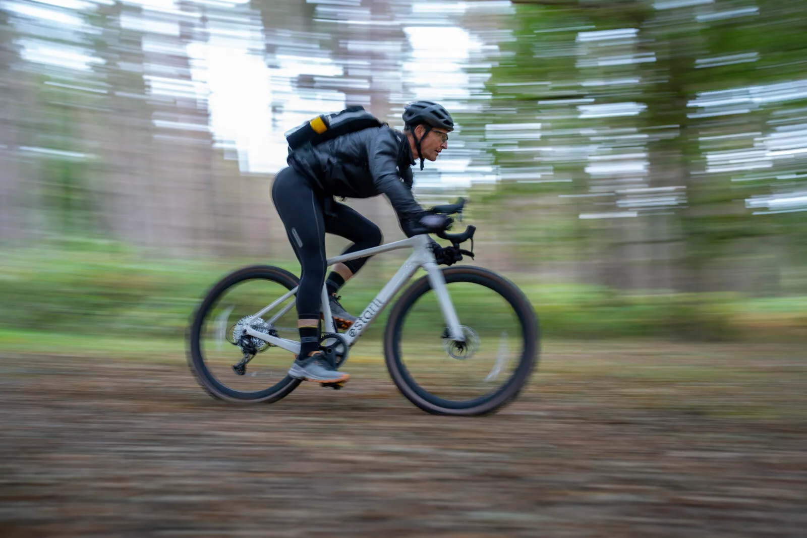A man riding the lunar white G700 at speed along a forest track.