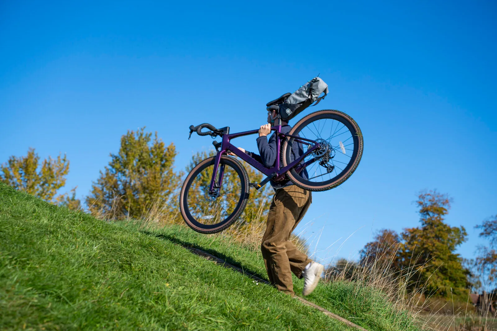 A man carrying the 13.5kg Estarli G700 up a grassy bank under blue skies.