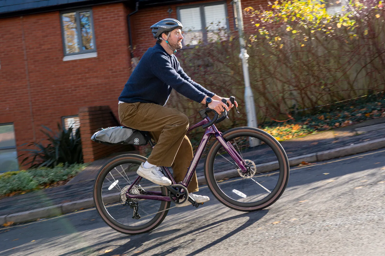 A man riding a cosmic purple G700 with a bikepacking seat pack along a residential street.