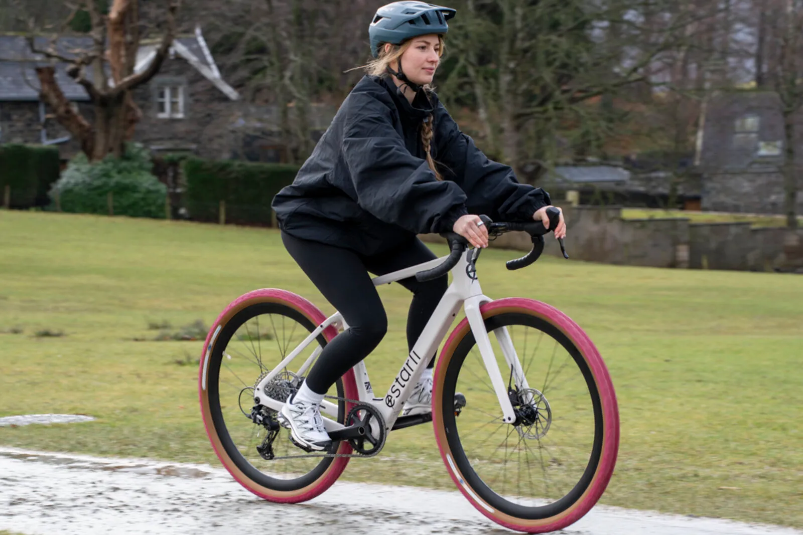A woman riding a lunar white Estarli G700 through a lakeside park.