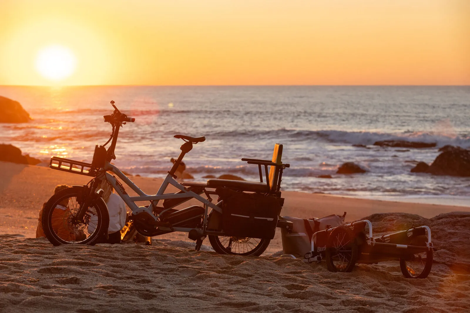 Two Tern GSDs and a trailer on a beach at sunset.