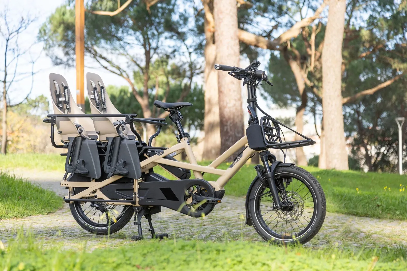 A satin beige Tern GSD fitted with two child seats and panniers in a park.
