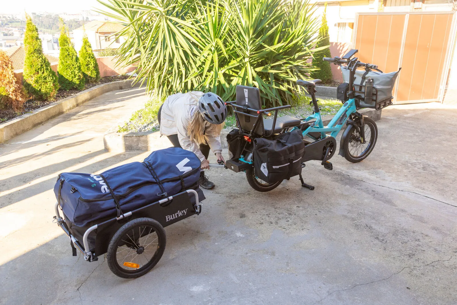 A woman loading a trailer beside two Tern GSDs on a driveway.