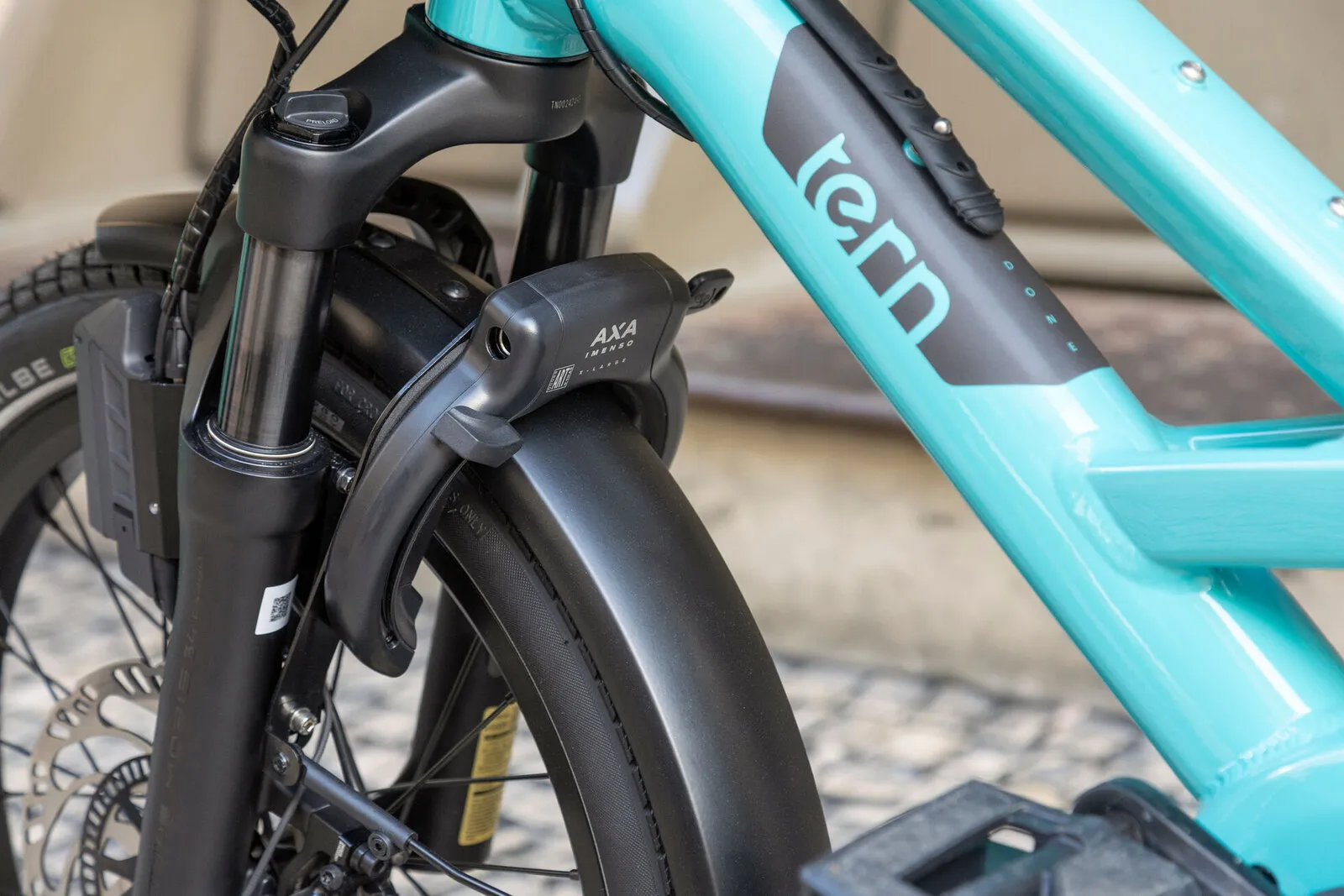 Close-up of the suspension fork, AXA frame lock and front disc brake on a beetle blue Tern GSD.