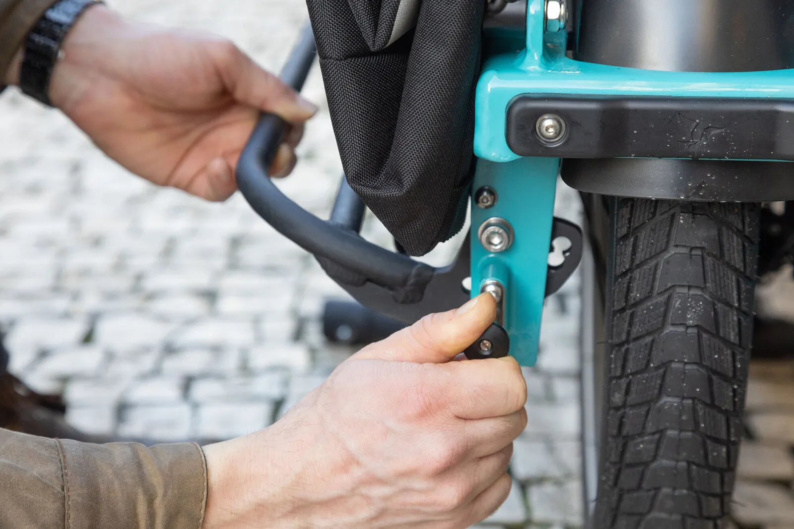A hand folding out the rear footrest on a beetle blue Tern GSD.