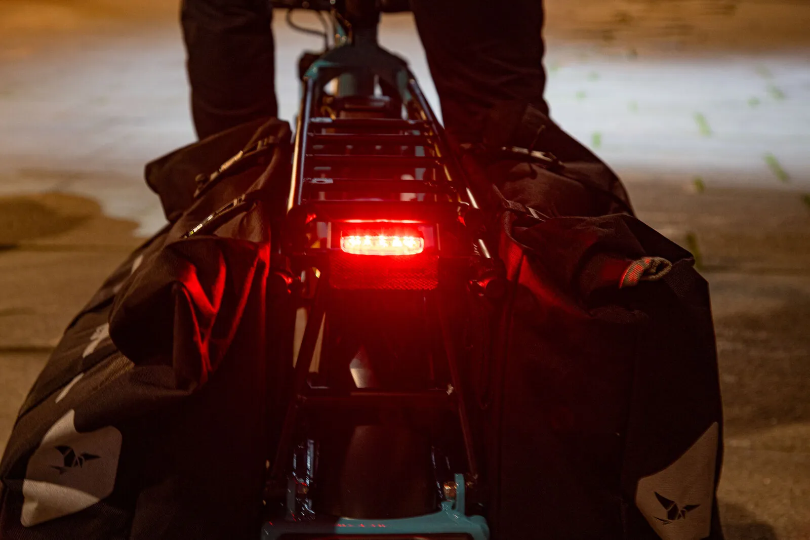 The rear brake light of a loaded Tern GSD lit up at night.