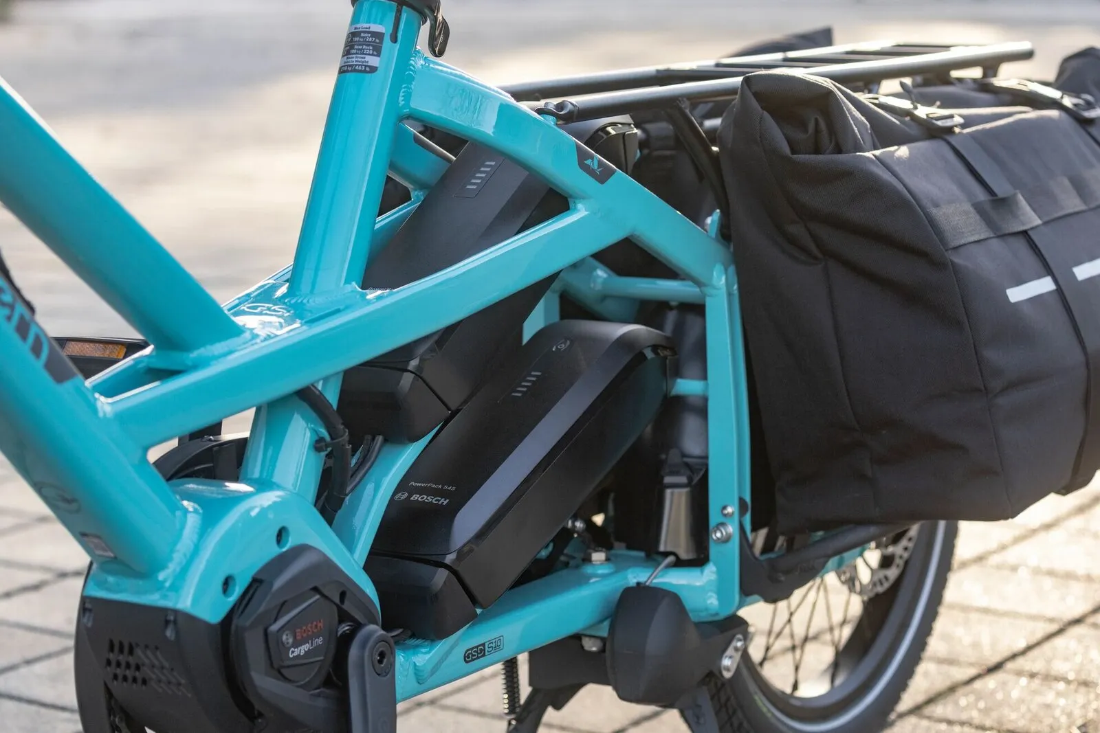 The dual battery bays of a beetle blue Tern GSD, with a pannier mounted behind.