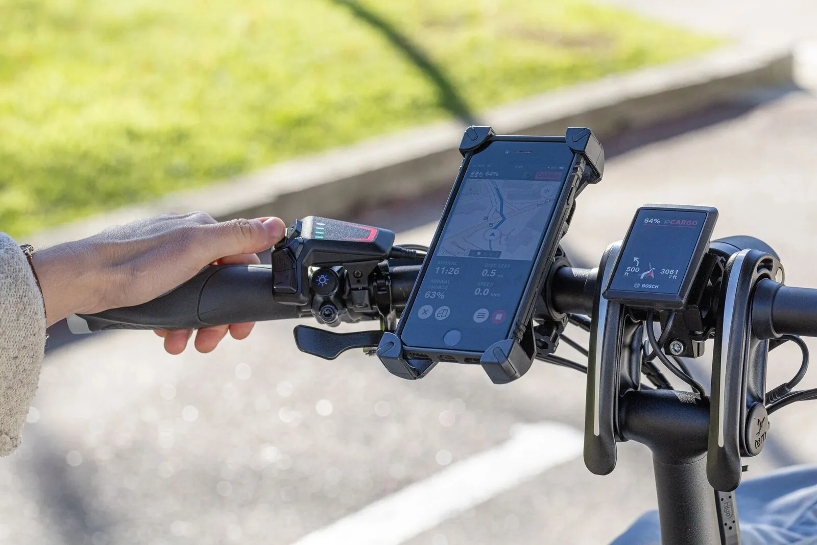 The handlebar of a Tern GSD with a smartphone mounted for navigation beside the Bosch display.
