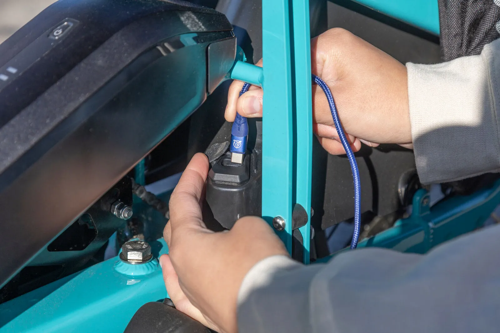 A hand plugging the charger into a beetle blue Tern GSD.