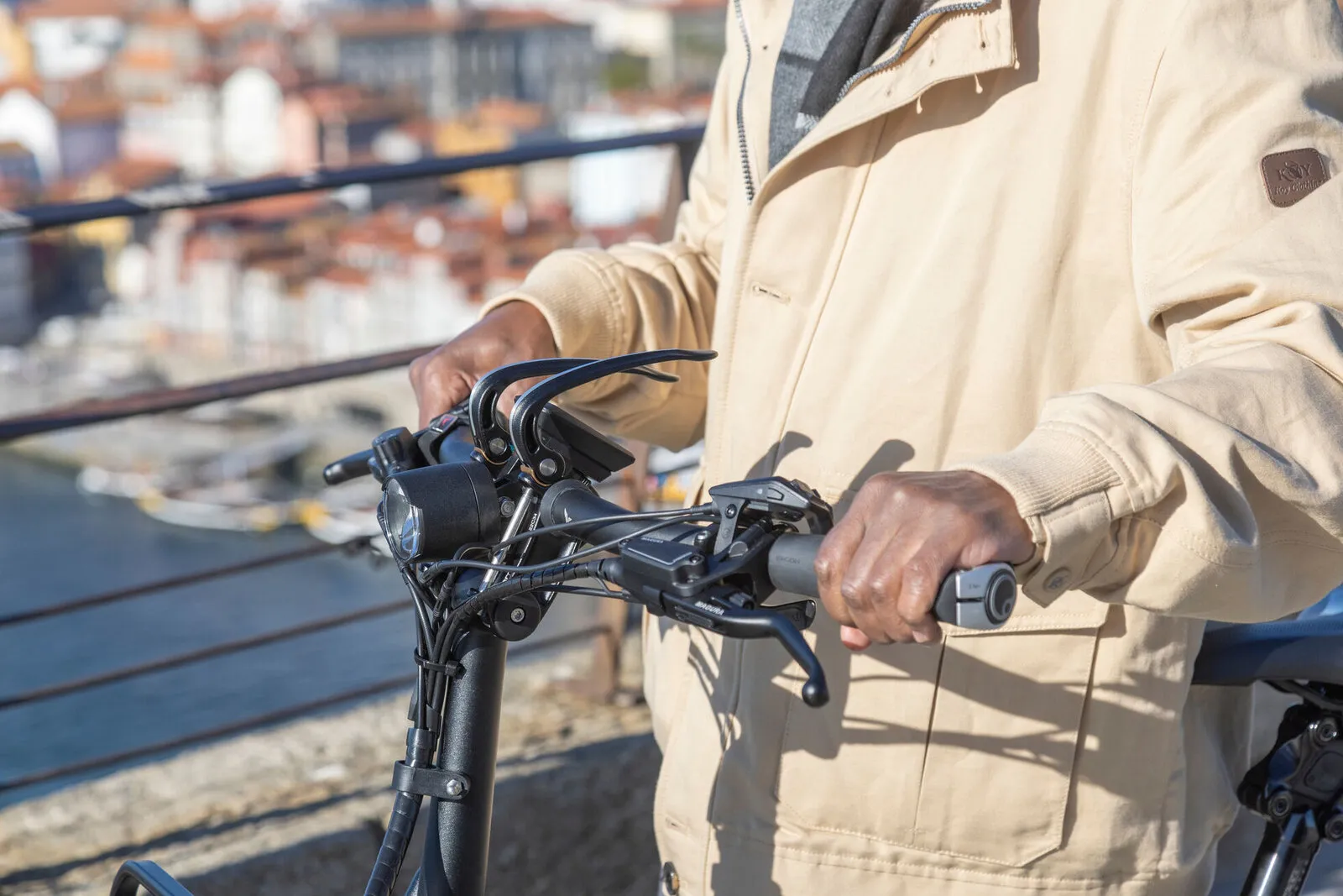 A rider's hands on the handlebar of a Tern GSD with a city skyline behind.