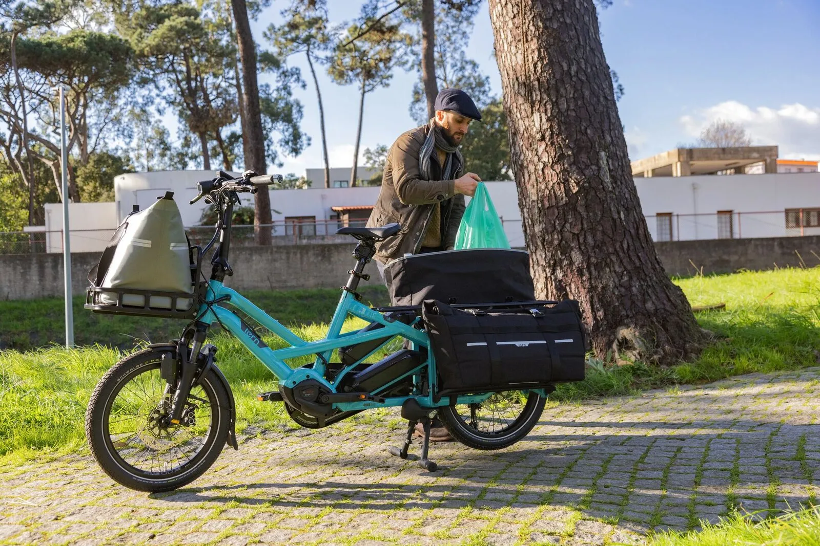 A man loading shopping into the panniers of a beetle blue Tern GSD fitted with a front rack bag.