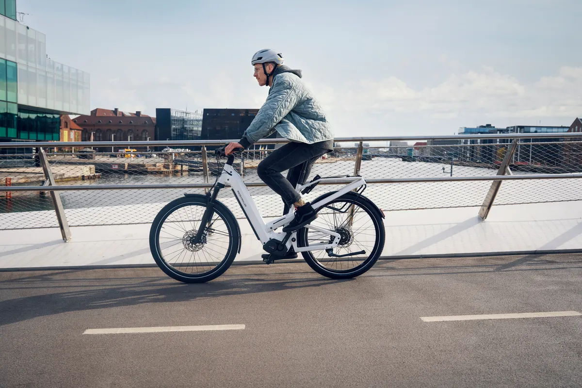 A man riding Riese & Müller’s Delite along a paved street in front of a textured marble wall.