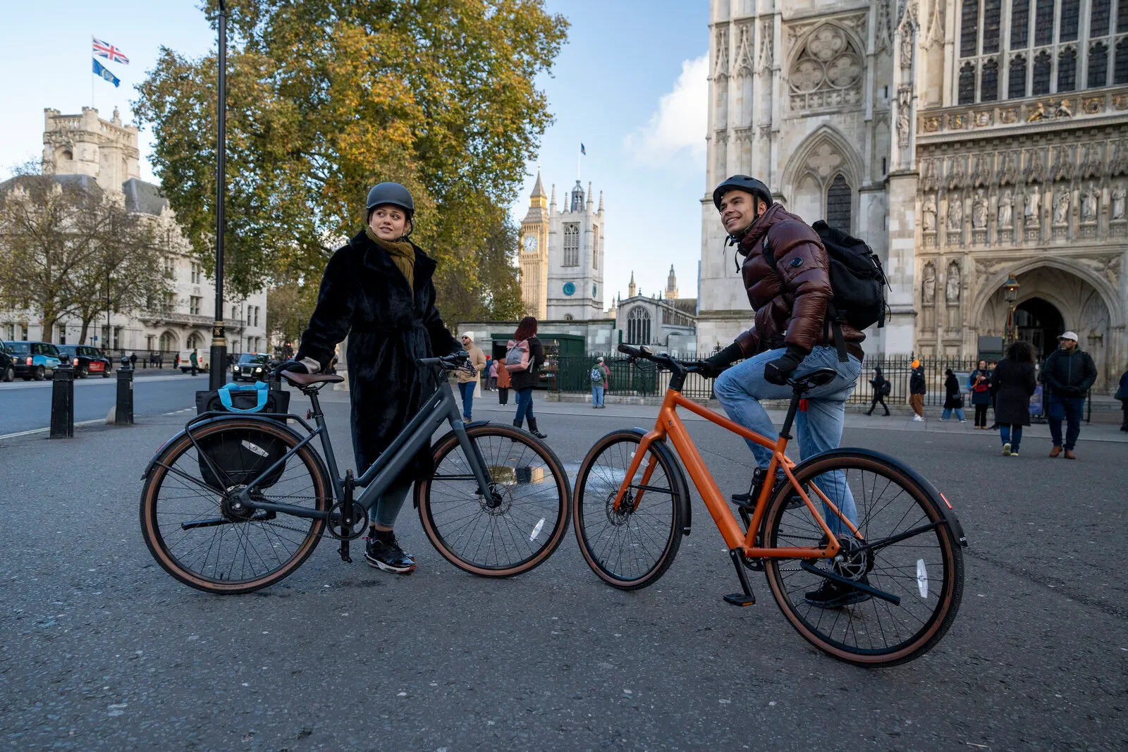 Two cyclists with Estarli e28.X bikes in midnight blue and bronze outside Westminster Abbey.