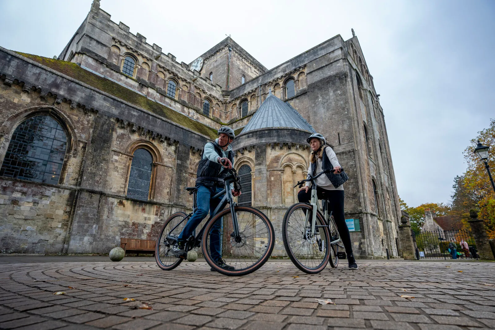 Two riders with Estarli e28.X bikes outside Romsey Abbey.