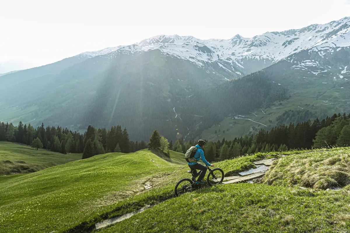 A man climbing a steep off-road trail on a Riese & Müller Superdelite mountain e-bike.