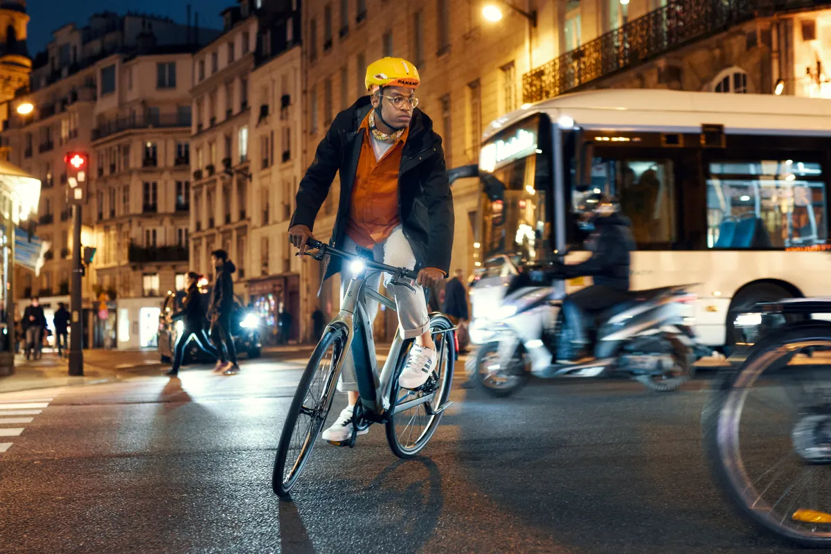 A man riding a Riese & Müller UBN Five in selva green through the busy streets of Paris.