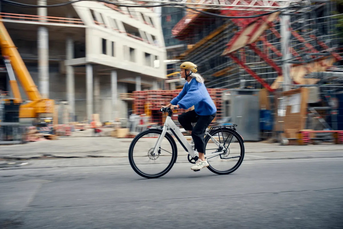 A lady riding a Riese & Müller UBN Six in pure white through busy streets.