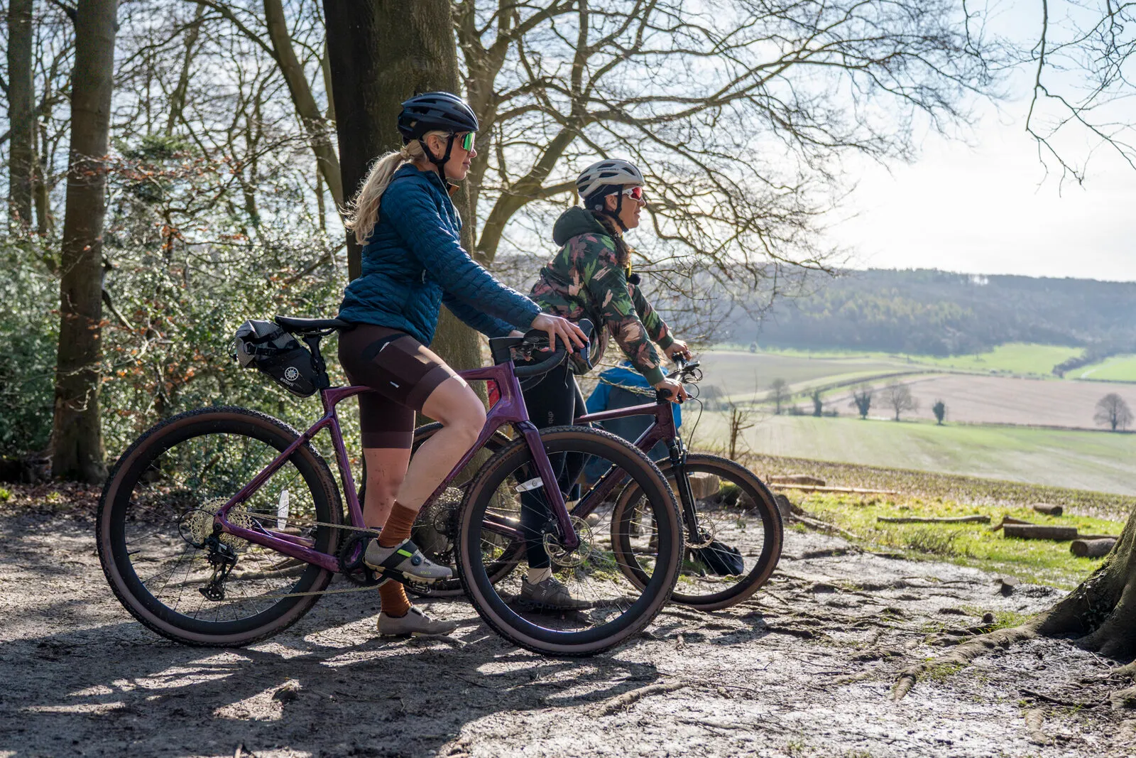 Two riders with Estarli gravel bikes looking out over farmland from a hilltop.